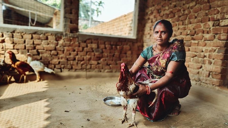 A woman kneels with her chicken.