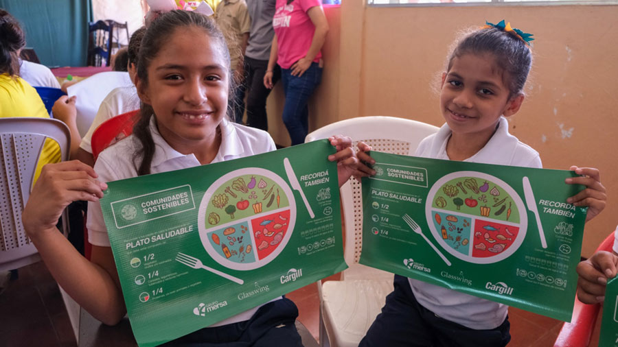 Two girls smiling with nutritional plan guides. 