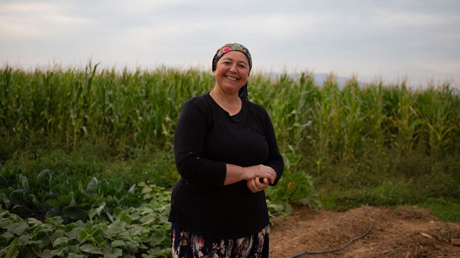 A female farmer stands in front of a field of green plants. A female farmer stands in front of a field of green plants.