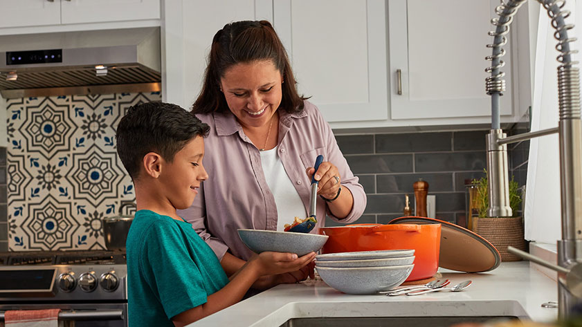  Mother and son cooking together, sharing a meal in their kitchen.