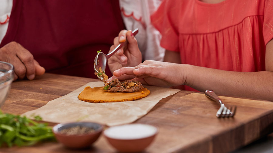 Close-up of a young girl filling an empanada with beef.