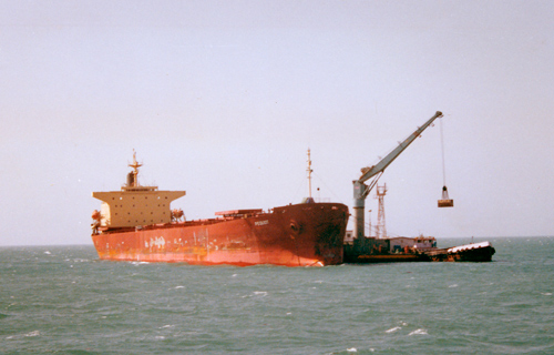 A ship unloads freight in the ocean waters outside India. A ship unloads freight in the ocean waters outside India.