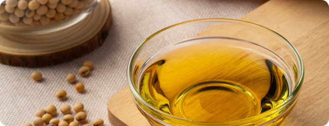 Soybean oil in glass bowl with soybeans on wooden table.Top view. Soybean oil in glass bowl with soybeans on wooden table.Top view.