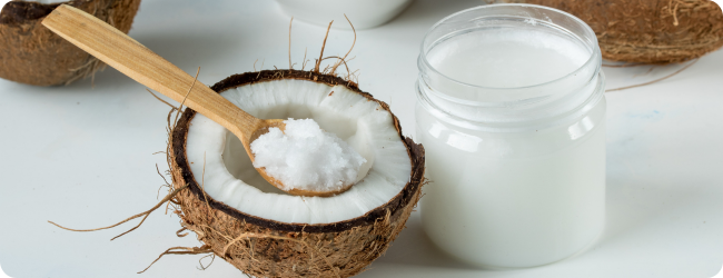 Coconut oil in a jar and coconut halves on the table on a white background Coconut oil in a jar and coconut halves on the table on a white background