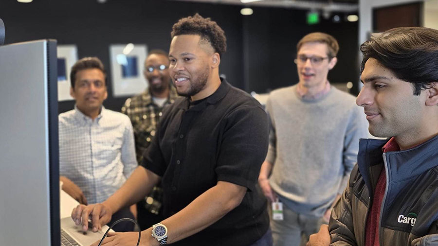 A team of data engineers stand at a desk to observe a demonstration. A team of data engineers stand at a desk to observe a demonstration.