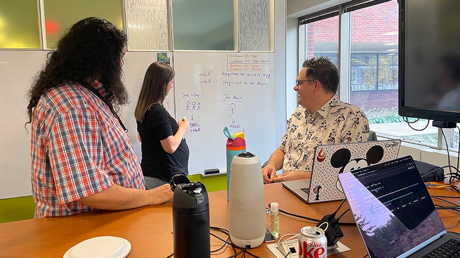 Cargill data engineer stands in front of a whiteboard as two people watch. Cargill data engineer stands in front of a whiteboard as two people watch.
