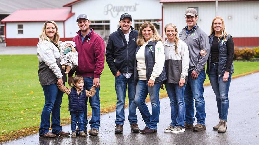 a family of nine people stand and smile outside a large building with Reyncrest written oni t. a family of nine people stand and smile outside a large building with Reyncrest written oni t.