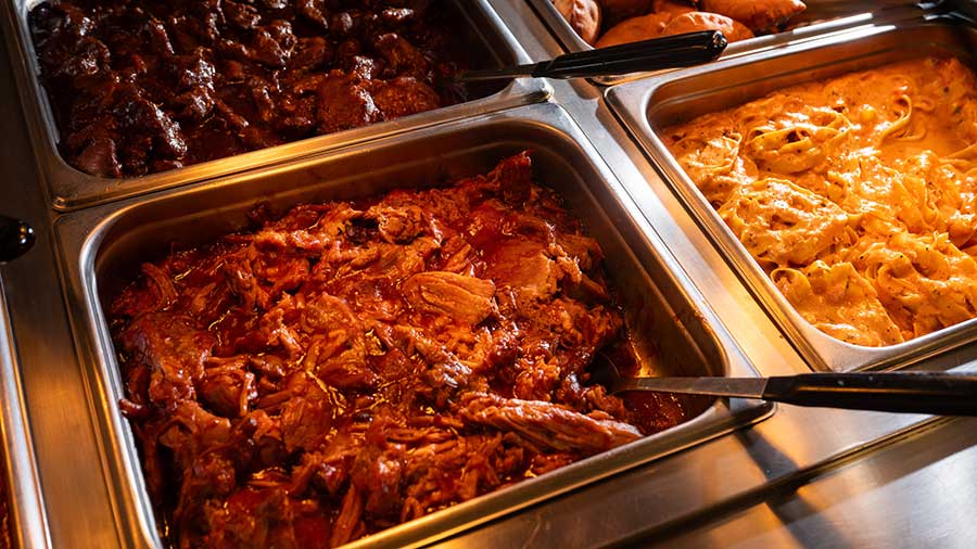Three bins of chicken in a hot bar with large spoons in each. 