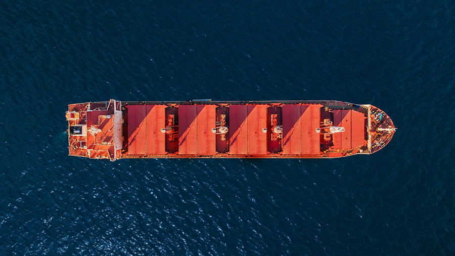 An overhead view of a large red container ship on the water. 
