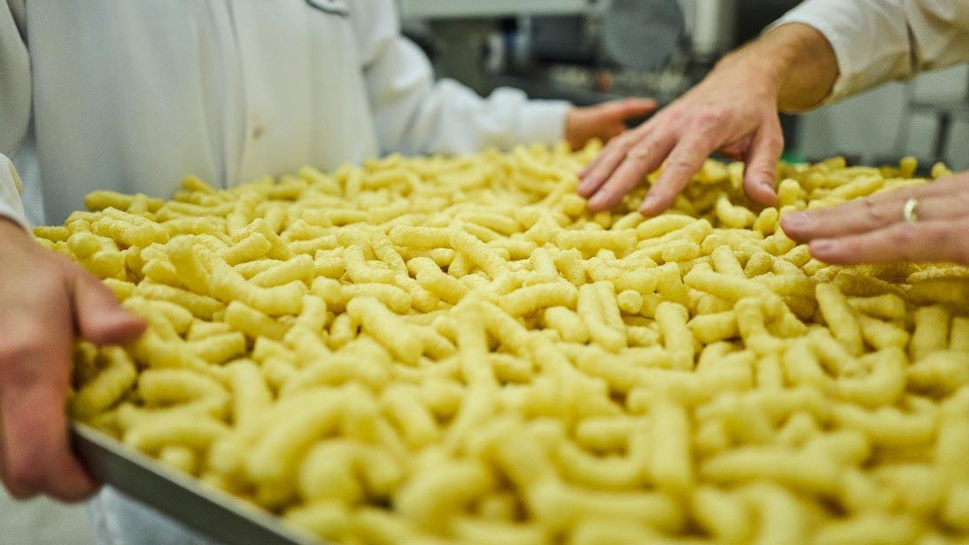 A Cargill scientist holds a large pan of protein-fortified puff snacks. A Cargill scientist holds a large pan of protein-fortified puff snacks.