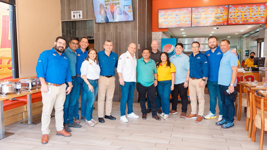 A group of people stand and smile inside a GoldChickenGold restaurant. 