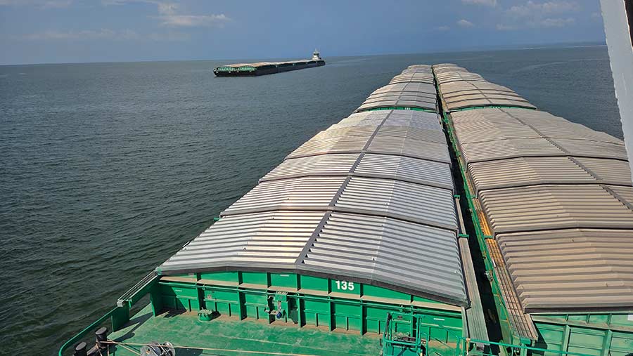 Several containers sit atop a barge being pushed through the water as another barge moves in the opposite direction, shipping across waterways that support global food security. 