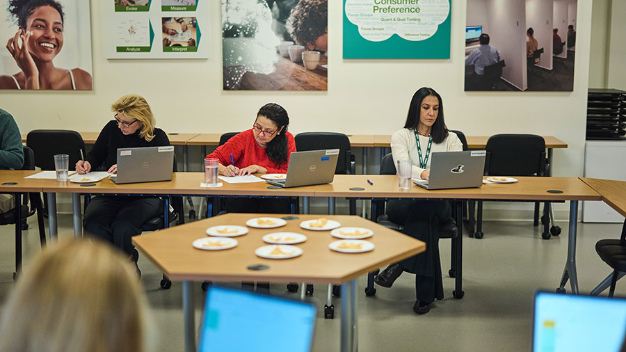 A group of people seated at tables, each using laptops in a collaborative workspace.