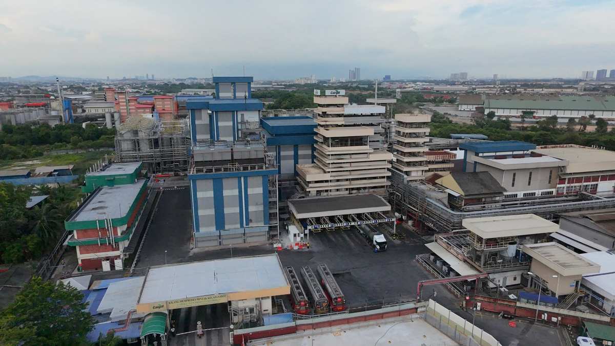 Aerial view of Cargill’s Port Klang plant featuring processing units, storage tanks, and logistics areas near a river and industrial zone.