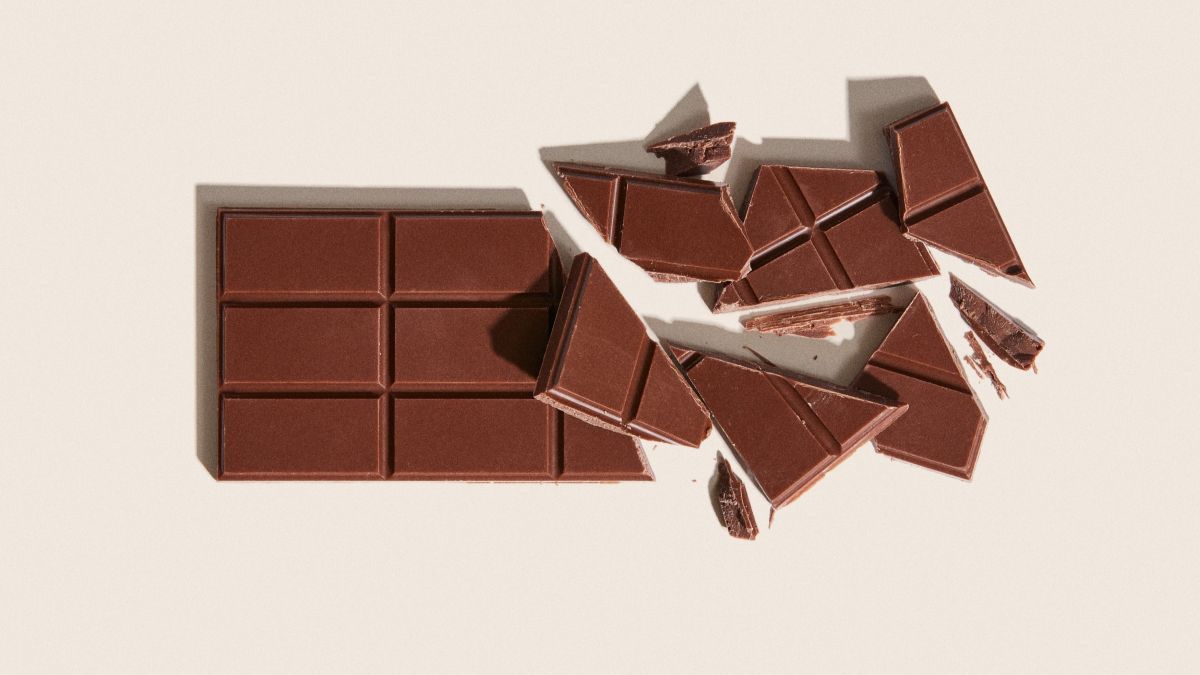 Chocolate bar partially broken into pieces on a light background.