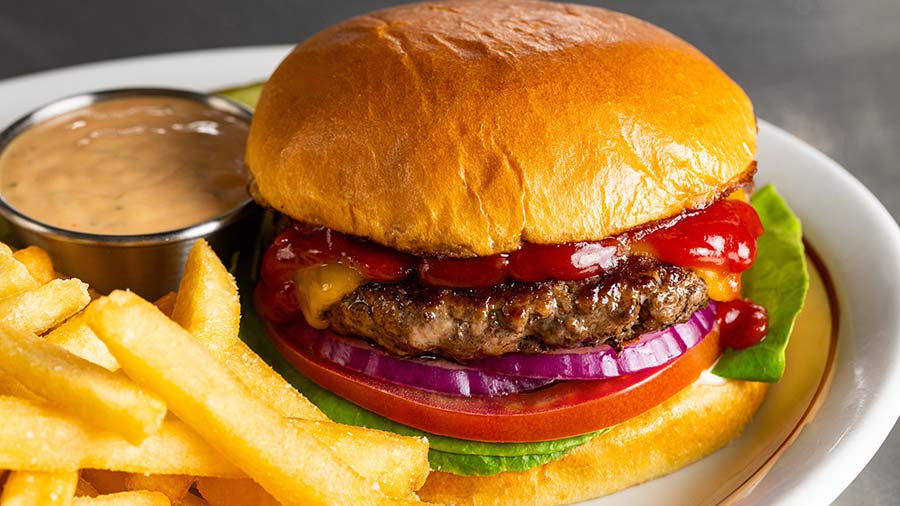 Beef burger with lettuce, tomato, red onion and sauce served with french fries and dipping sauce. Beef burger with lettuce, tomato, red onion and sauce served with french fries and dipping sauce.