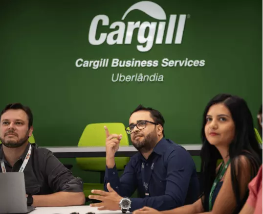 Foto mostrando funcionários da Cargill, dois homens e uma mulher, participando de uma reunião, todos olhando para a mesma direção