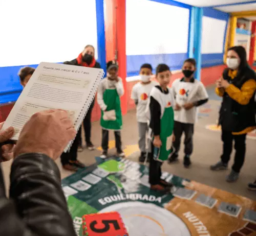 Foto de crianças participando de uma atividade educativa lúdica sob orientação de adultos